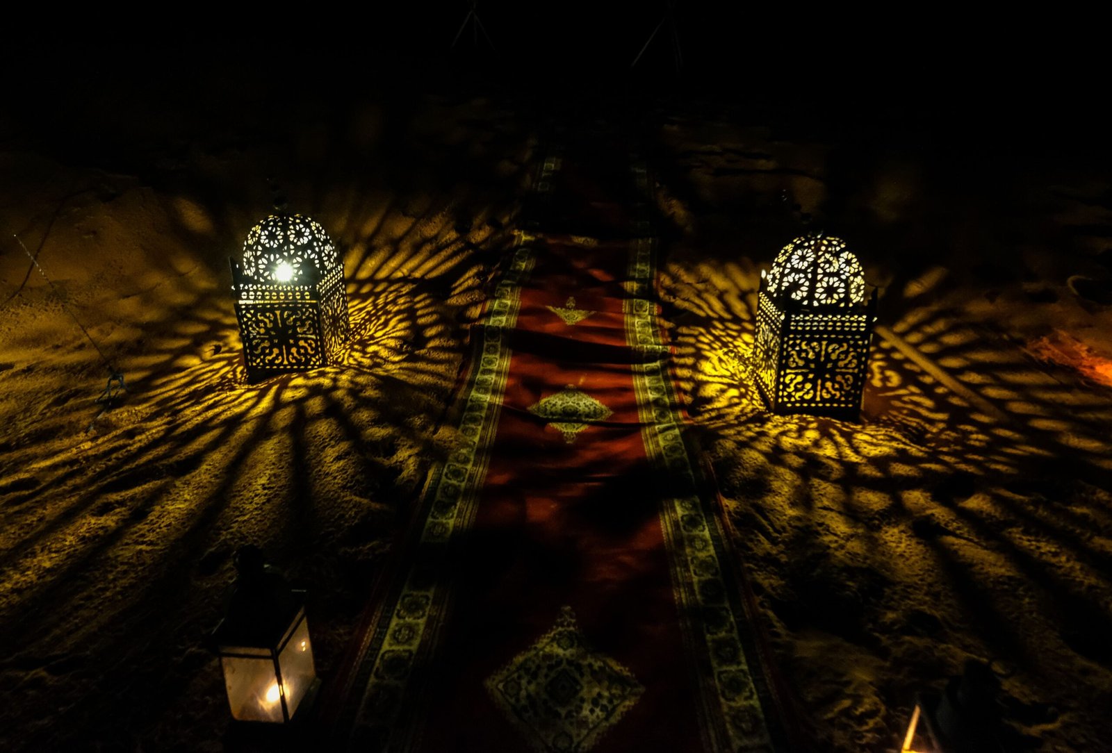 Moroccan lanterns glowing on desert sand at night in the Sahara