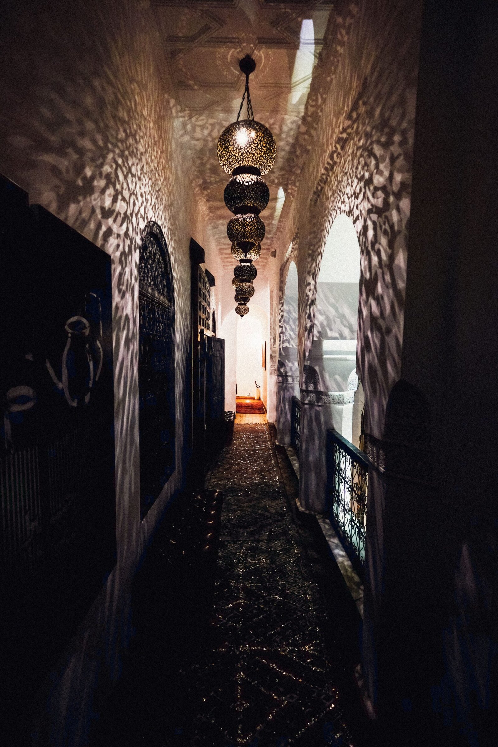 Warm lantern light along a dim traditional Moroccan corridor